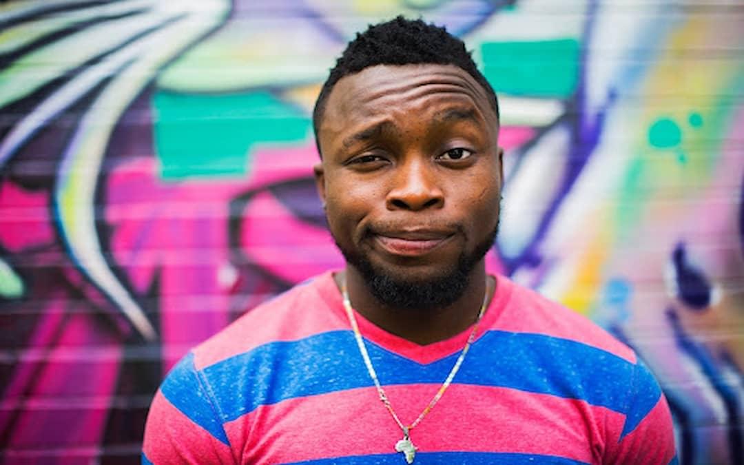 Man in front of graffitied wall smirking